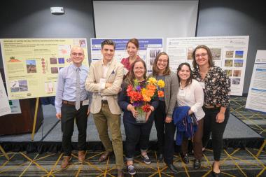Environmental Science graduate and undergraduate students pose for a photo in front of their research posters